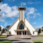 Contemporary cathedral church architecture visualization in Kiambu Kenya: central tower, large arched entrance, stained glass details, fountain forecourt, mature trees, by Cadreatech